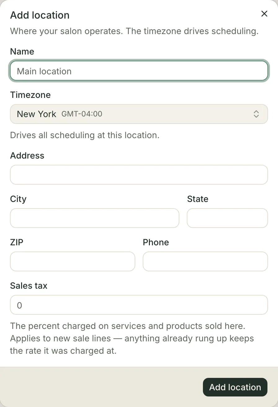 The Add location dialog: an empty name field, a timezone picker already reading New York with its GMT offset under a line saying it drives all scheduling at this location, then empty address, city, state, ZIP and phone fields, a Sales tax field placeholdered 0 under a line saying it is the percent charged on services and products sold here and that it applies to new sale lines, and an Add location button.
